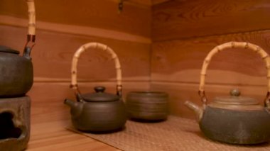 Kil çaydanlığı, el yapımı çay seremonisi için diğer toprak malzemelerinin yanında, odasındaki ahşap bir rafta.