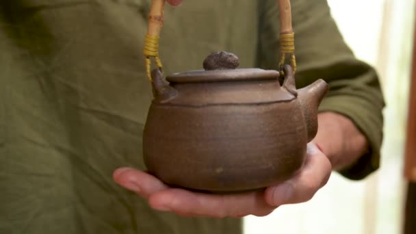 Um oleiro masculino mostra seu trabalho Yixing bule de barro para uma cerimônia de chá artesanal nas proximidades. Profundidade de campo rasa — Vídeo de Stock