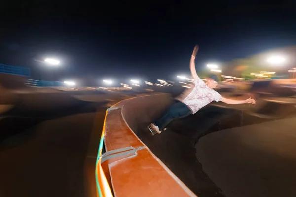 Ruch w rozmytym, młodym łyżwiarzu toczy się nocą po rampie w skateparku. Technika Flash z ruchem przewodów — Zdjęcie stockowe