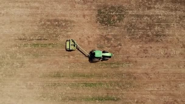 Вид с воздуха на трактор с косилкой косит траву на пустом поле. Подготовка и техническое обслуживание месторождений в течение года — стоковое видео