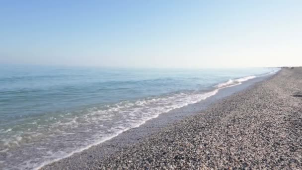 Uma praia deserta de manhã em tons azuis, pequenas ondas rolam sobre a costa arenosa. Olhar sobre o mar — Vídeo de Stock