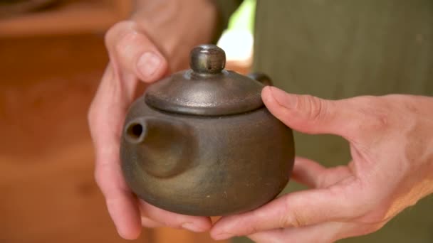 Een mannelijke pottenbakker toont zijn werk Yixing klei theepot voor een handgemaakte theeceremonie in de buurt. Ondiepe scherptediepte — Stockvideo