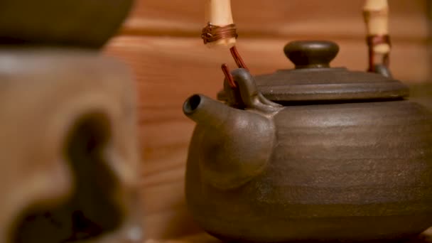Tetera de arcilla Yixing para una ceremonia de té hecha a mano junto a otros utensilios de barro en un estante de madera en la habitación — Vídeo de stock