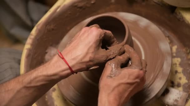Close-up van een pottenbakker die een kleikom maakt op een pottenbakkerswiel van klei — Stockvideo