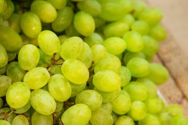 Bir sebze dükkanında tezgahın üzerinde bir demet beyaz üzüm yatıyor..