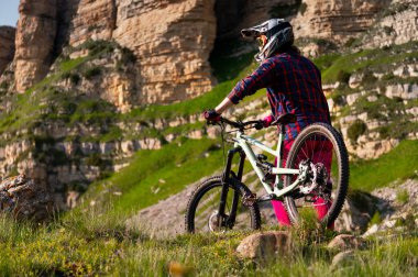Tepenin tepesinde dinlenen erkek turistin güzel dağ manzarasının tadını çıkarırken yüzünü kaplayan kaskla görüntüsü. Etkin aşırı eğlence kavramı.