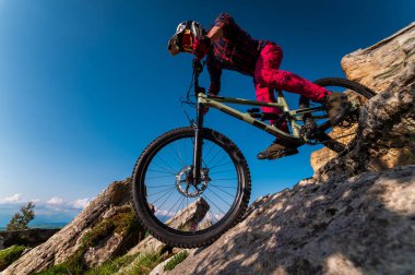 Dağ bisikletçisi çimenli bir yamaçtan aşağı iniyor. Enduro dağ bisikleti. Bir dağ manzarasına karşı MTB.