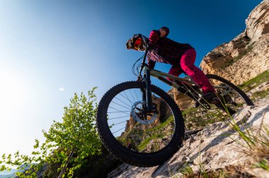 İsviçre Alplerinde dağ bisikleti. Kayalık dağları ve mavi gökyüzünü hayret verici bir şekilde gören bisikletli bir sporcu, yolun keskin açısı, yüksek hızla alçalıyor..