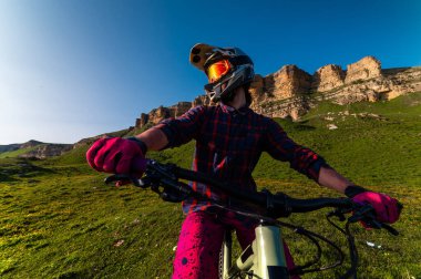 Spor haberleri. Bir bisikletçi tarlada tek başına durur. Yokuş aşağı bisiklet süren biri.