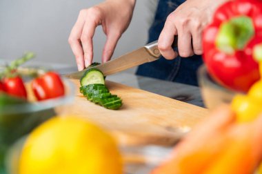 Sağlıklı beslenmek için mutfakta yeşil sebzeli pano ve salata. Evde salata, salatalık ve organik malzemelerle öğle yemeği hazırlayan kişi..