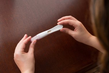 Close-up of Hand Holding Home Pregnancy Test Showing Faint Positive  clipart