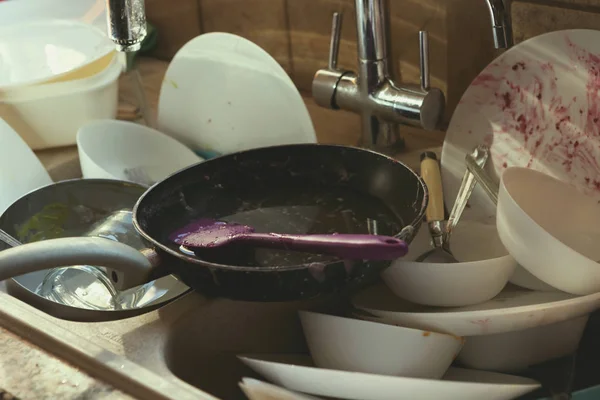 A Messy Pile of Dirty Dishes And Utensils In Kitchen Sink