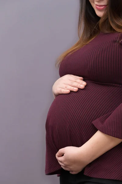 Aanstaande moeder holding haar ontluikende baby bump — Stockfoto