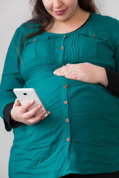 Expectante jovem mãe à procura em seu smartphone — Fotografia de Stock