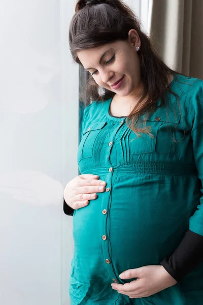 Sonriente embarazada mamá holding su incipiente bebé golpe — Foto de Stock