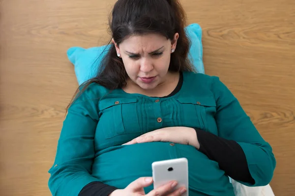 Aspettativa giovane mamma alla ricerca sul suo smartphone — Foto Stock