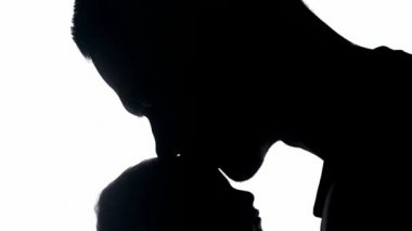 Yeni doğan çocuğu alnından öpen yeni babanın silueti