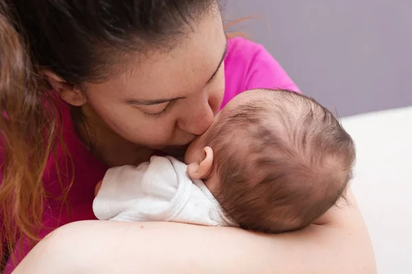 Mãe amorosamente beijando seu bebê recém-nascido — Fotografia de Stock
