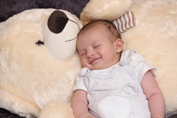 Smilende baby dreng sover med stor bamse - Stock-foto