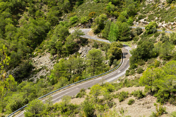 A section of road with bends going through  mountainous countryside