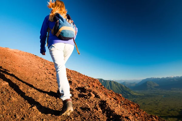 女ハイカーは夕日の間に谷の景色を与え山に登る — ストック写真