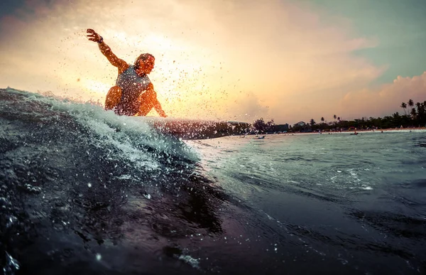 年轻的冲浪运动员在日落时乘风破浪 — 图库照片