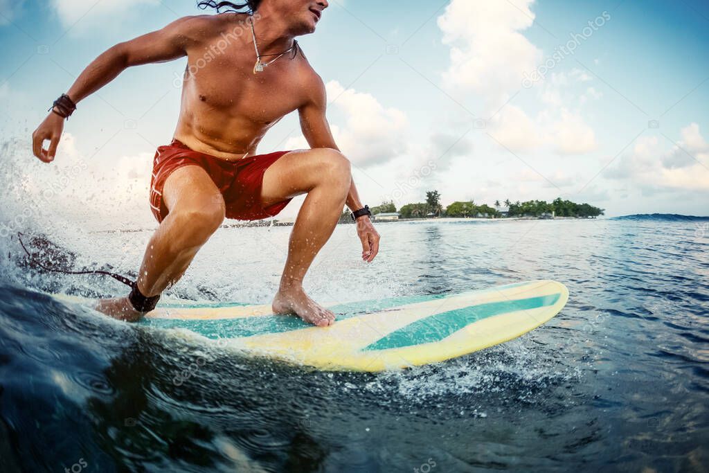 Young man surfer rides the ocean tropical wave during sunrise surf session