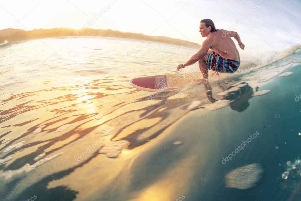 Surfer rides the wave in tropics at sunrise. Costa Rica