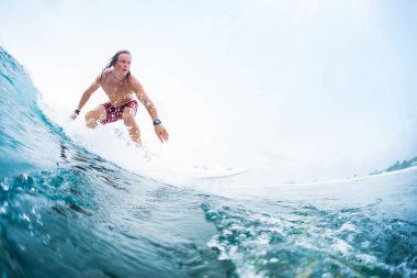 Genç sörfçü tropik bir okyanusta sörf yapıyor. Maldivler