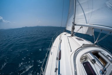 Yelkenli teknesi ufukta zar zor görünen adaların olduğu bir denizde hareket eder. Tayland