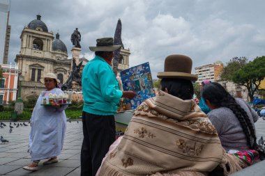 LA PAZ, BOLIVIA - 24 Mart 2018: İki yerli Bolivyalı kadın Plaza Murillo 'nun merdivenlerinde oturur ve sokak satıcılarından dondurma alırlar