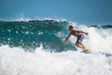 Amatör sörfçü okyanus dalgalarına biner.