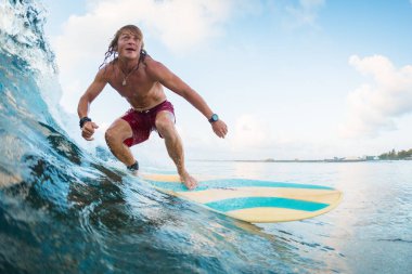 Genç sörfçü okyanusta tropikal dalgalarda sörf yapıyor
