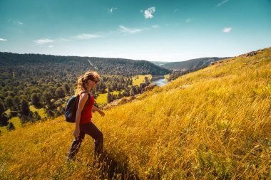 Kadın yürüyüşçü ufukta dağla tepede yürüyor. Ural Dağları, Rusya