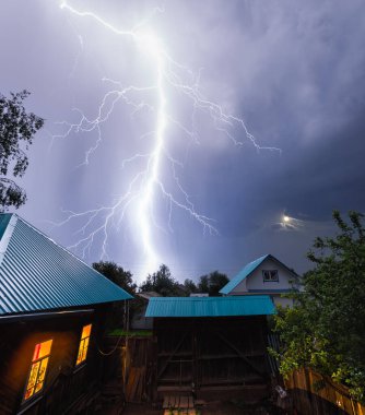 Gece gökyüzünde şimşek çakıyor köyün üzerinde evler ve bahçeler