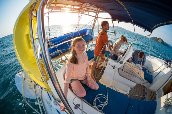 Young team sails in a tropical sea at sunset