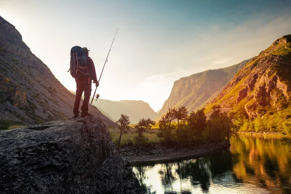 徒步旅行者背着背包和钓竿站在岩石上 欣赏日出的江景 — 图库照片