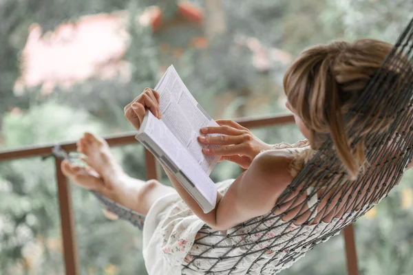 Žena Letních Šatech Leží Houpací Síti Zahradě Čte Knihu — Stock fotografie