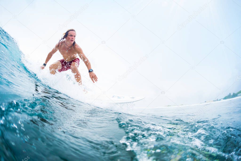 Young surfer rides an ocean tropical wave. Maldives