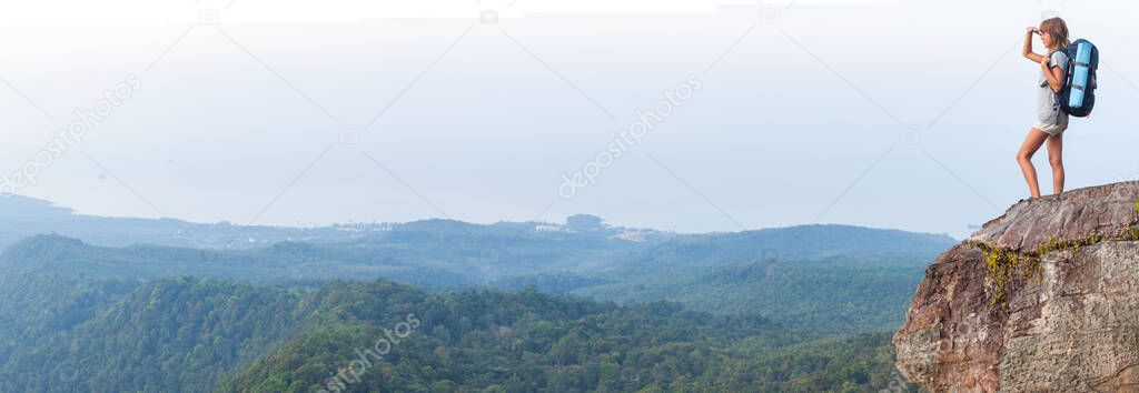 Panorama with young woman hiker standing on the cliff with backpack