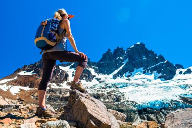 Woman hiker stands on the rocks and enjoys glacier view of the Cerro Castillo Mountain, Patagonia, Chile. clipart