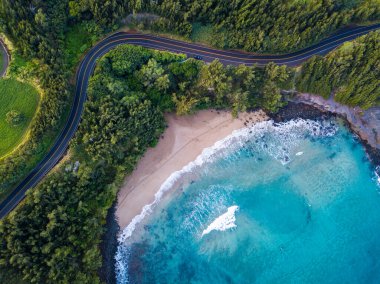 Maui 'nin batı kıyısındaki kumlu sahil manzarası ve eğri asfalt yol. Hawaii