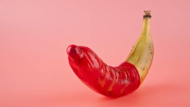 muz ve kırmızı prezervatif pembe bir arka plan üzerinde