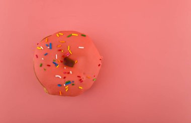 Pembe arka planda pembe kremalı donut.