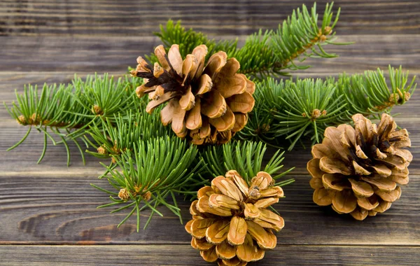 Christbaumzweig Und Zapfen Auf Einem Hölzernen Hintergrund — Stockfoto