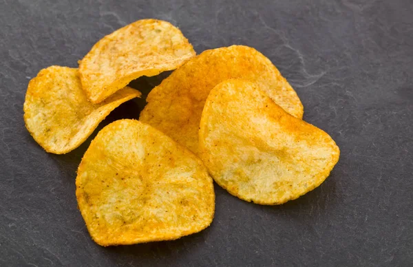 Crispy potato chips on a black stone background — Stock Photo, Image