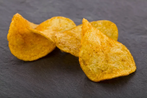 Crispy potato chips on a black stone background — Stock Photo, Image