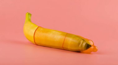 Pembe arka plan yakın çekim üzerinde prezervatif muz