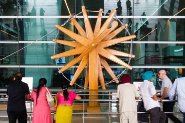 NEW DELHI, INDIA - CIRCA APRIL 2017: People stand in front of the world's largest charkha (spinning wheel) at Indira Gandhi International Airport. clipart