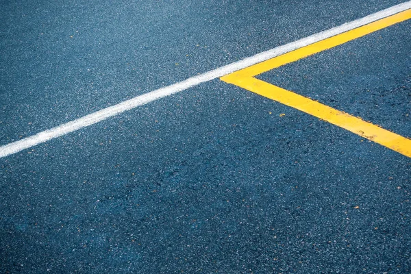 Superfície de asfalto com linhas brancas e amarelas — Fotografia de Stock